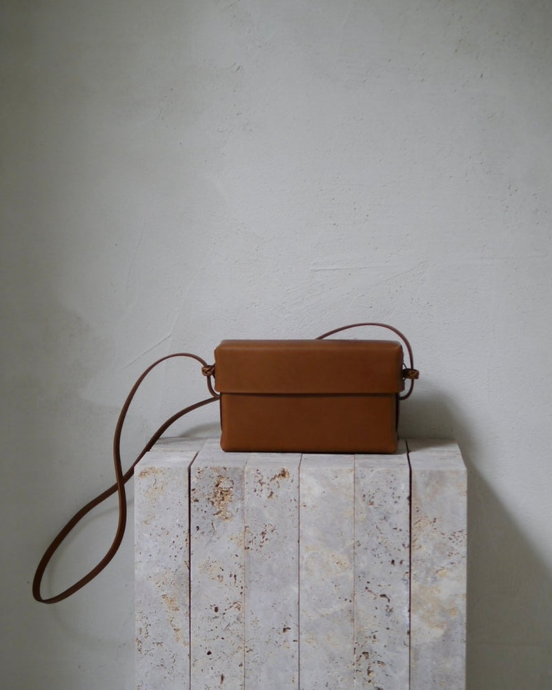 Brown leather handbag on a textured surface with a neutral background