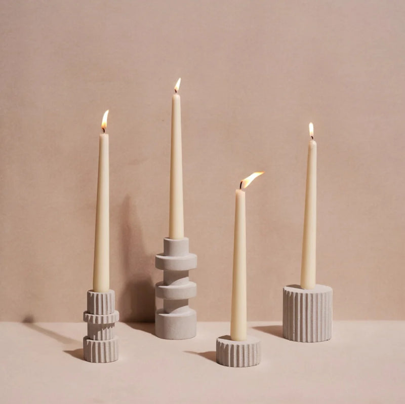 Four candle holders with lit candles on a beige background