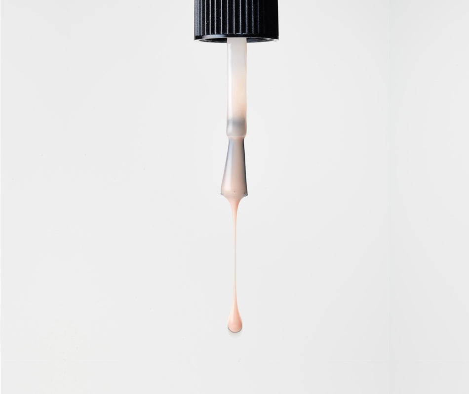 Dropper nail polish brush with blush liquid on a white background