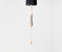 Dropper nail polish brush with blush liquid on a white background