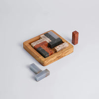 Set of stone puzzle pieces with a wood base on a light gray background