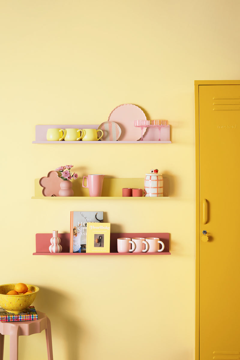 Shelves with decorative items against a yellow wall with a locker.
