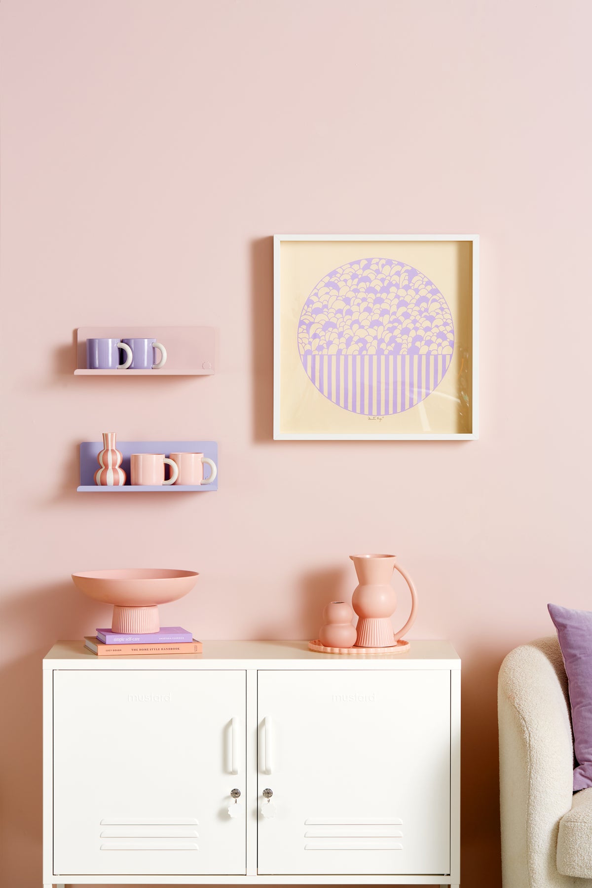 Decorative wall shelf with a cabinet, vases, and a framed picture on a pink wall.