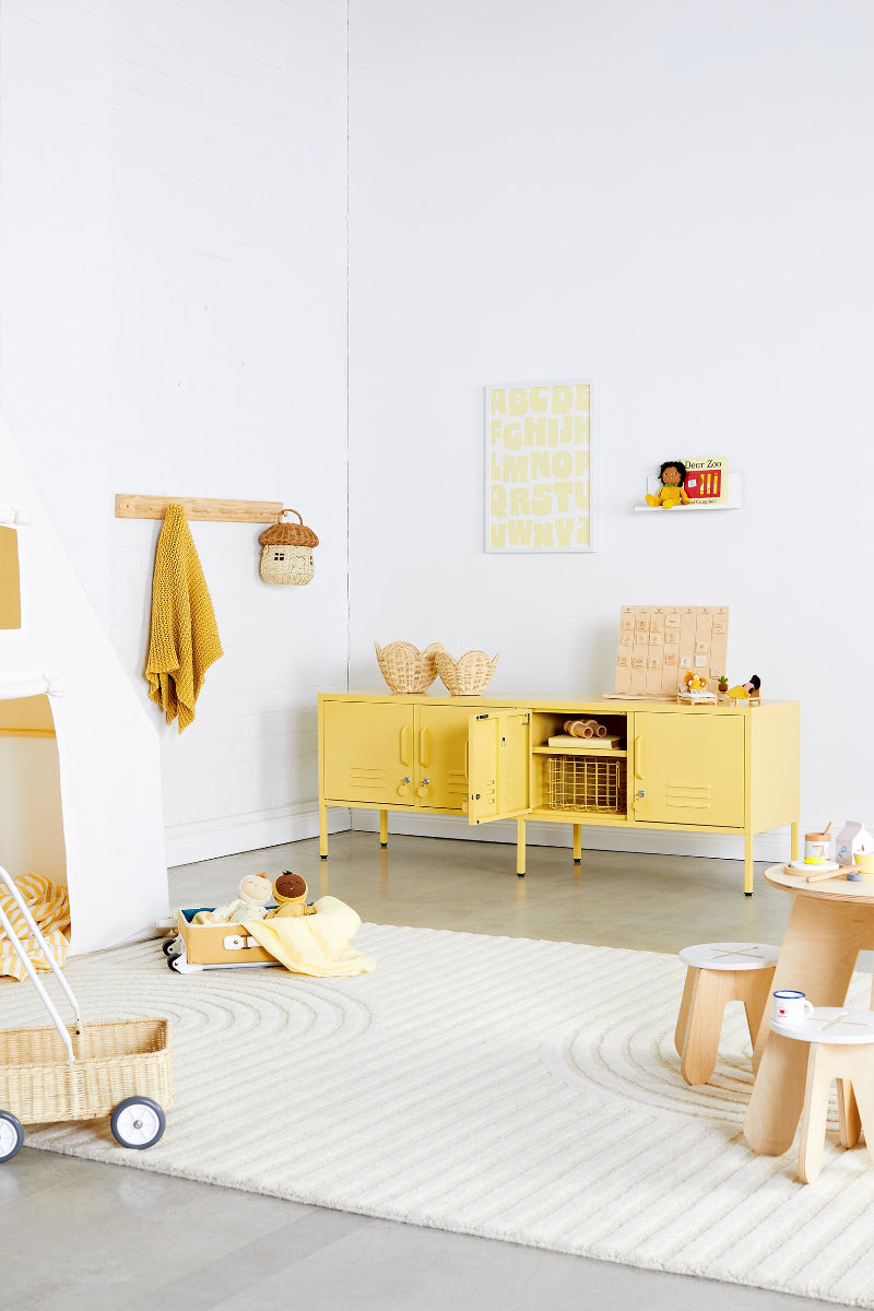 Children's room with yellow cabinet, toys, and a rug on a light gray floor.