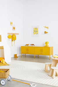 Children's room with yellow cabinet, toys, and decor on a white wall.