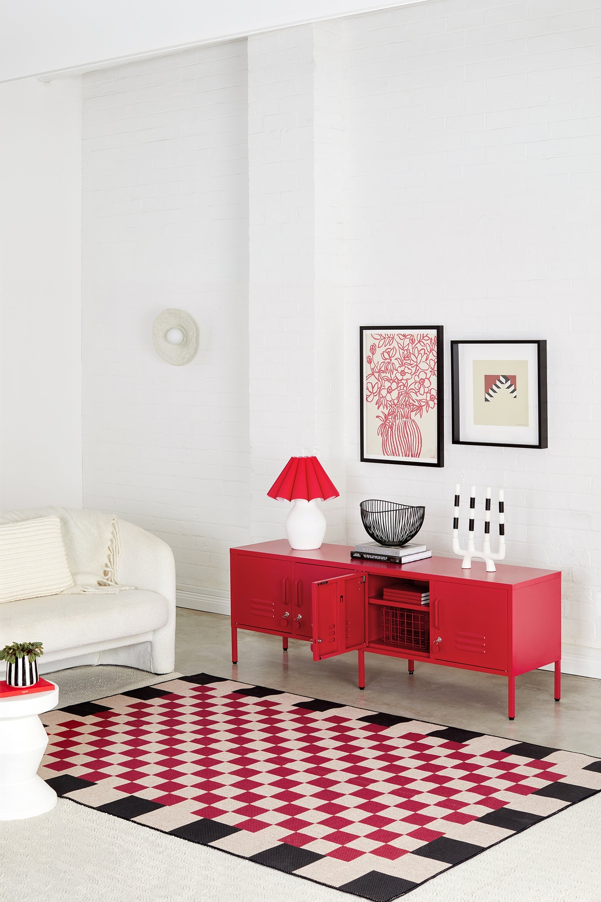 Modern living room with a red cabinet, white sofa, and geometric rug.