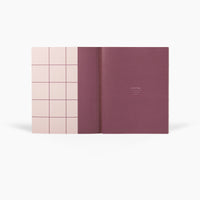 Pink and purple notebook with grid design on a white background