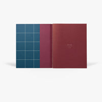 Open journal with a blue grid pattern cover and burgundy inside pages on a white background