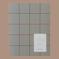 Gray grid pattern notebook with a white card on a brown background