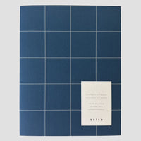 Blue grid pattern notebook with a white card displaying text on a gray background