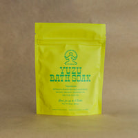 Yellow bag of Yuzu Bath Soak with green text on a Kraft paper background
