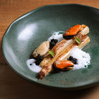 Gourmet dish with seafood and vegetables on a green ceramic plate.