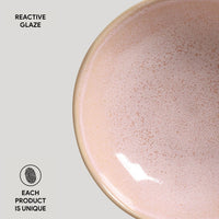 Pink ceramic bowl with reactive glaze on a light gray background