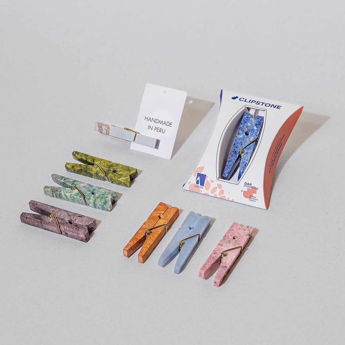 Rows of colorful stone clothespins with packaging and notecard that says 'Handmade in Peru'