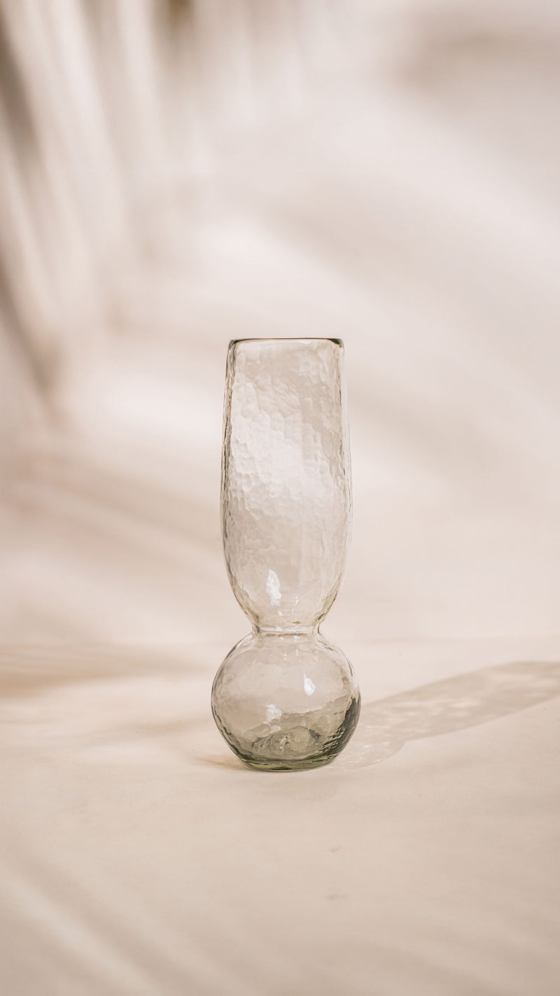 Clear glass vase on a textured beige surface