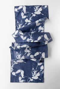 A blue and white patterned table runner folded on a white background