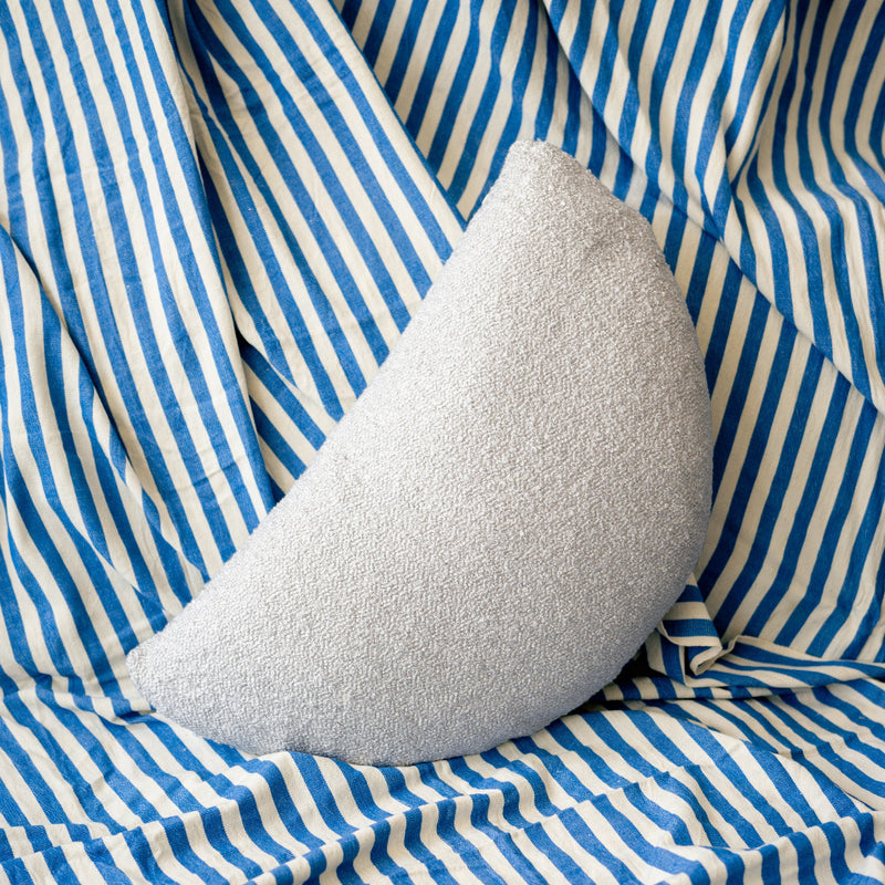 Silver textured pillow on a blue and white striped fabric background