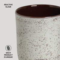 Ceramic cup with reactive glaze on a light gray background