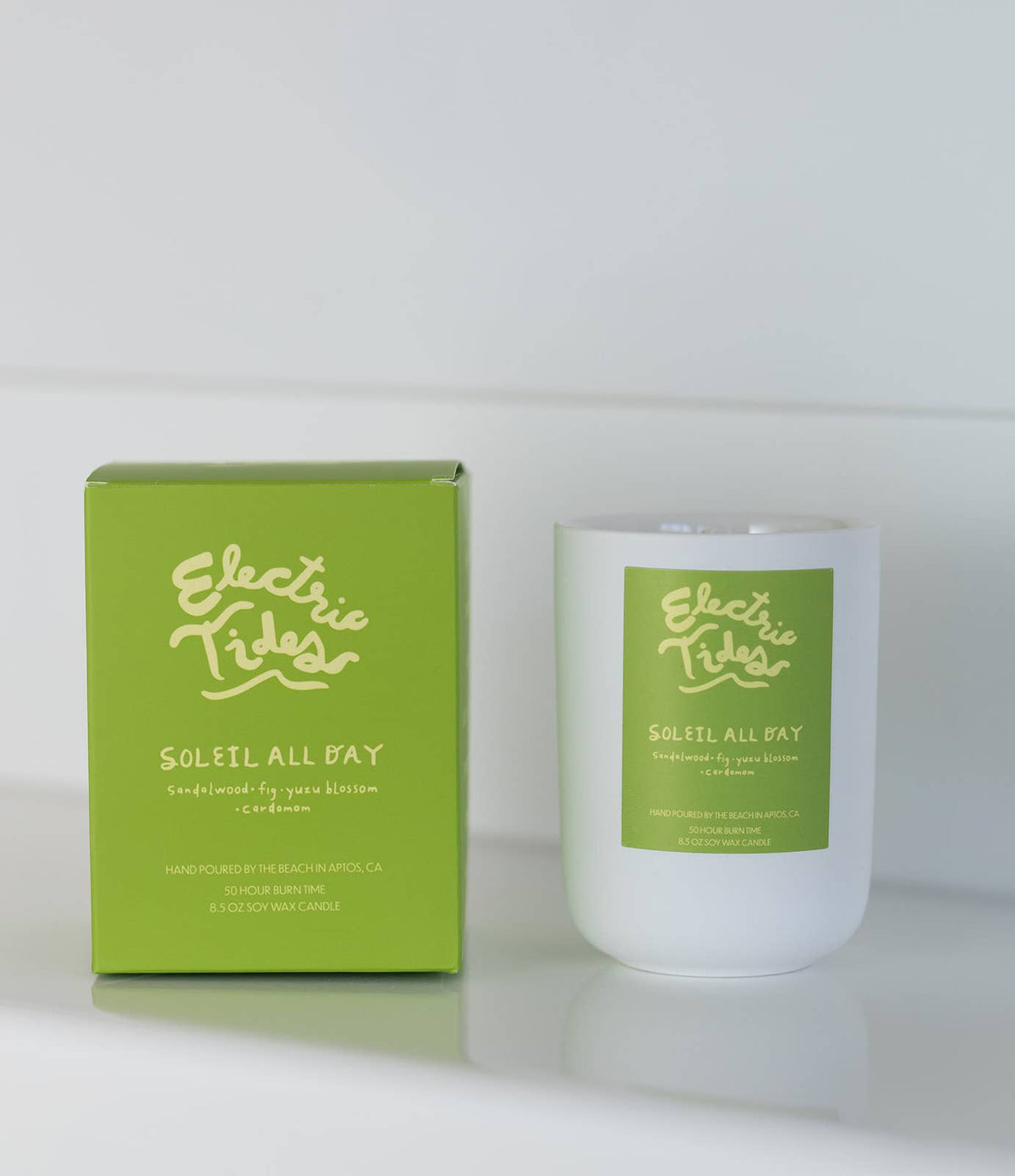 Candle and packaging with 'Electric Tides' branding on a white background