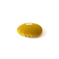 Round mustard yellow cushion on a white background
