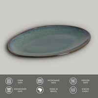 Oval ceramic plate with blue glaze on a gray background