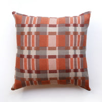 Checkered pillow with orange, brown, and beige pattern on a white background