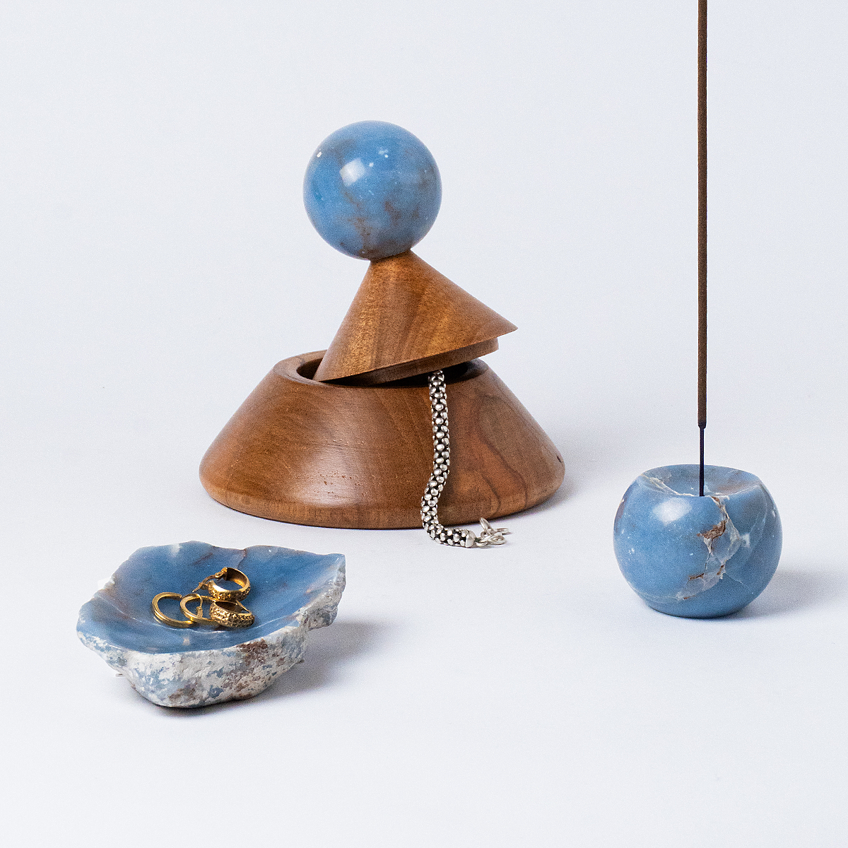 Wooden box with blue spherical top and base, accompanied by a small dish  and spherical incense holder on a light gray background.
