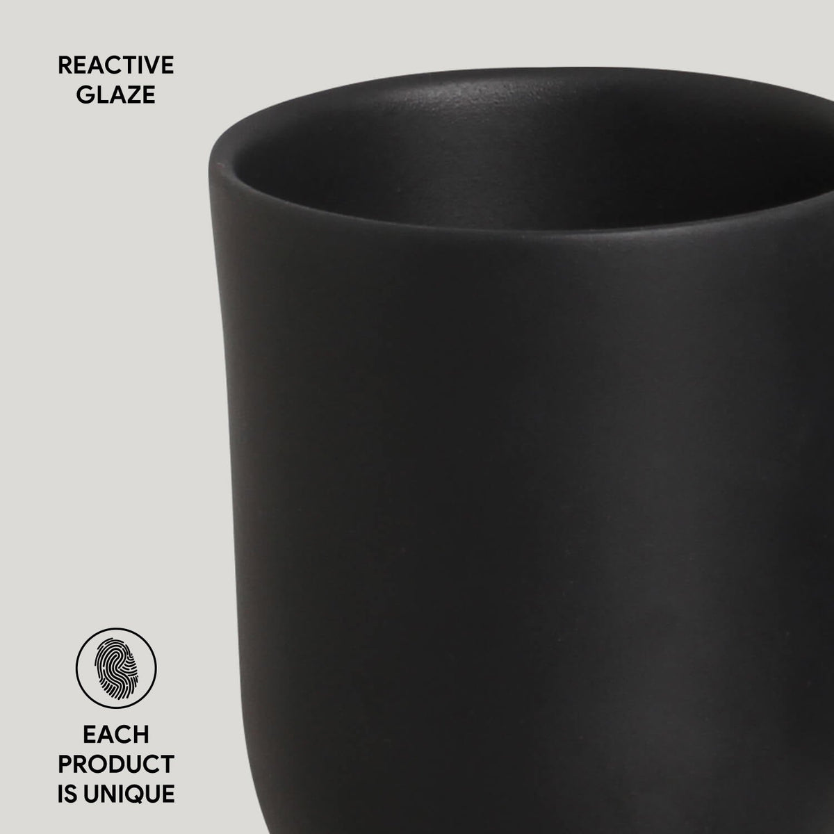 Black ceramic cup with 'Reactive Glaze' text and 'Each product is unique' label on a light gray background