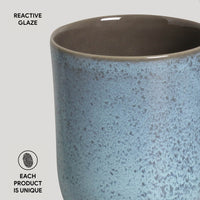 Ceramic mug with reactive glaze finish on a light gray background