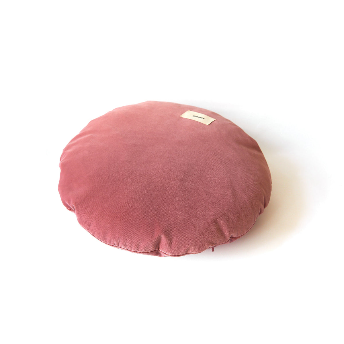 Round pink cushion with a small label on a white background