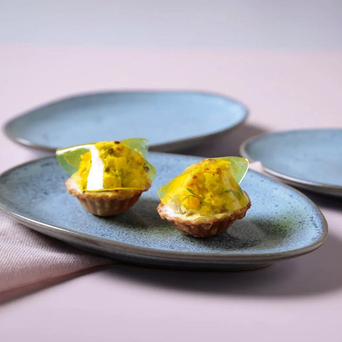Two small appetizers on a blue plate with a blurred background