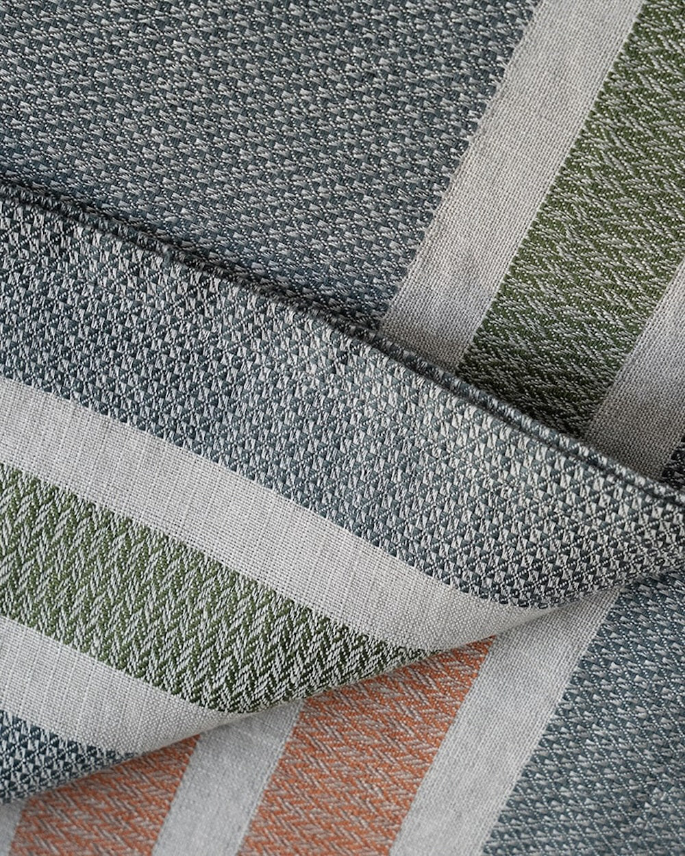 Close-up of woven towel fabric with a geometric pattern in gray, green, and orange.