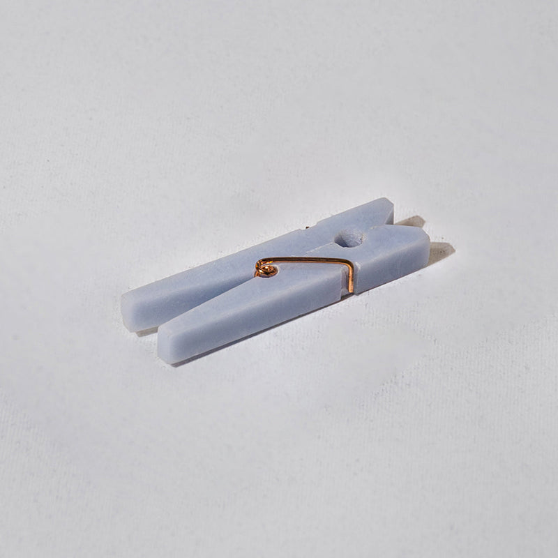 Light blue stone clothespin with a gold clip on a white background