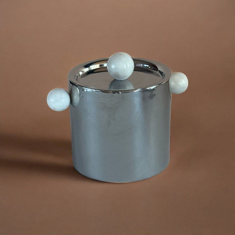 stainless steel ice bucket with marble sphere handle accents on a brown background