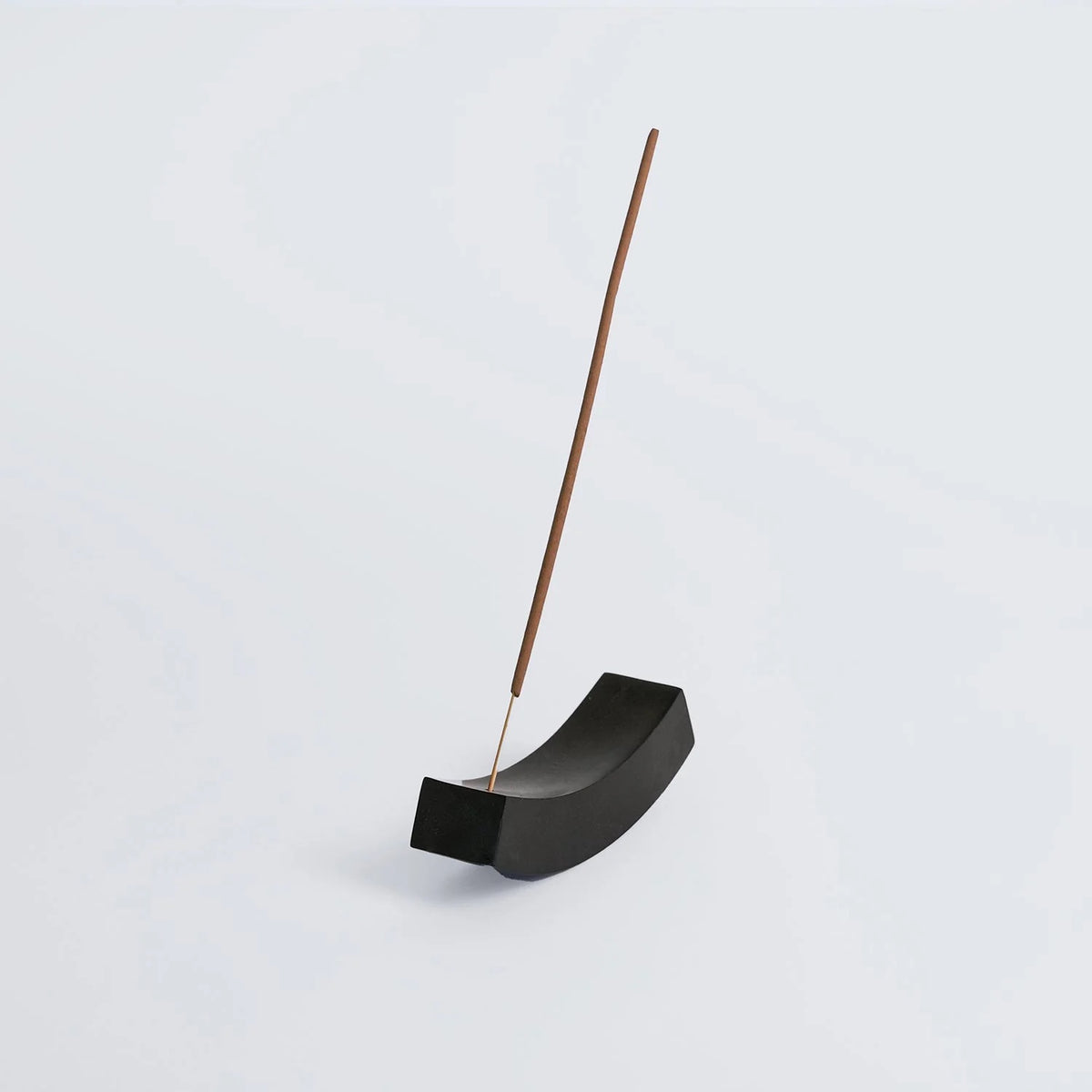 Black onyx incense holder with a wooden incense stick on a light gray background