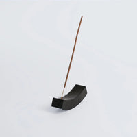 Black onyx incense holder with a wooden incense stick on a light gray background