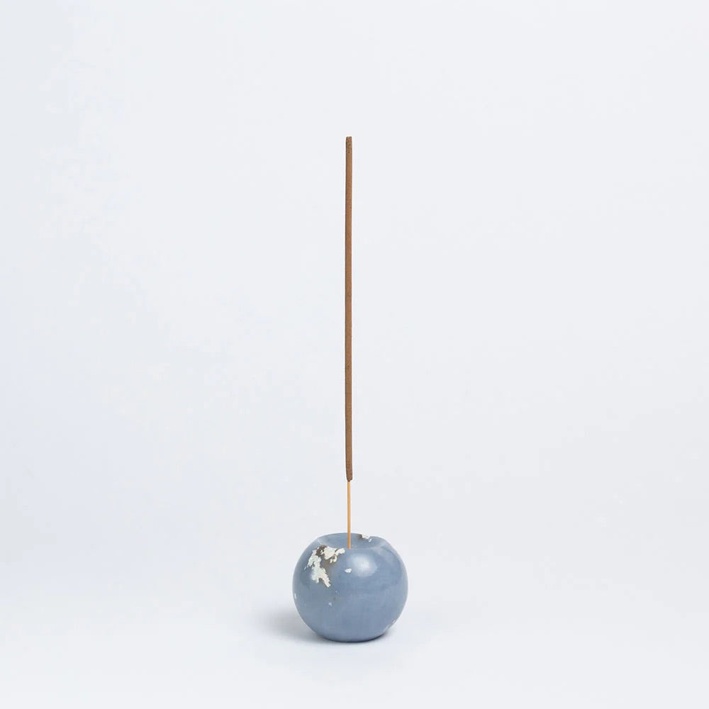 Blue stone incense holder with a single incense stick on a white background