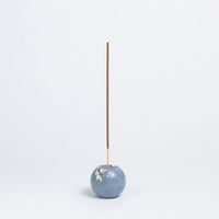 Blue stone incense holder with a single incense stick on a white background