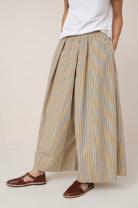 Person wearing striped wide-leg pants and brown sandals on a plain background