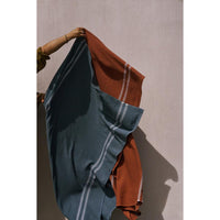 Person holding towels with blue and rust colors against a plain background