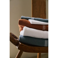 Stack of folded towels on a wooden stool with a neutral background