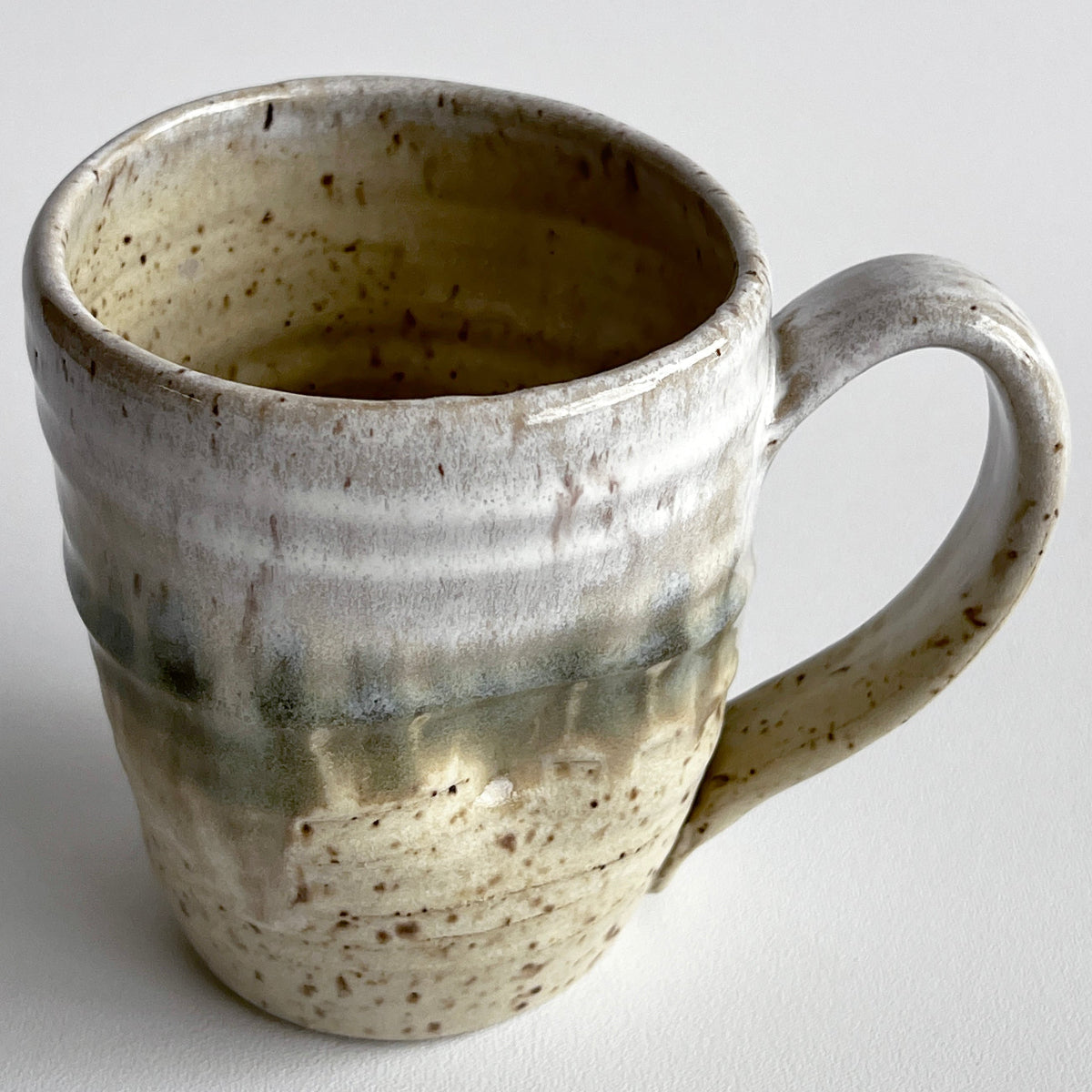 Ceramic mug with light and dark neutral glaze details on a white background