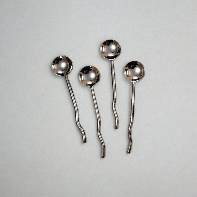 Set of four silver spoons on a light gray background
