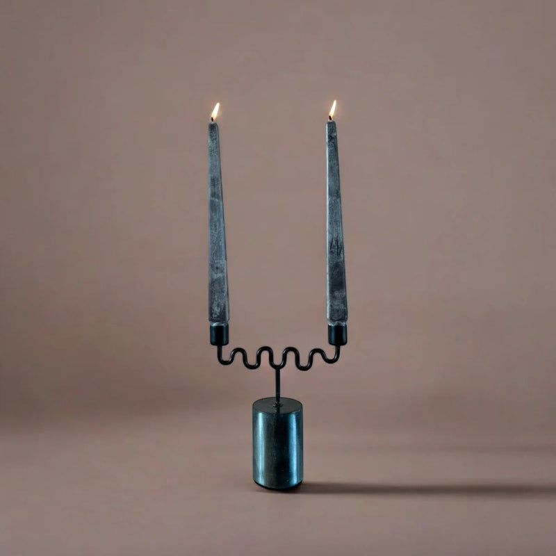 Candle holder with two lit candles on a beige background