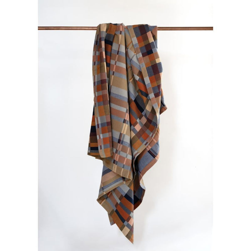 Plaid multi-color blanket draped over a wooden rod 