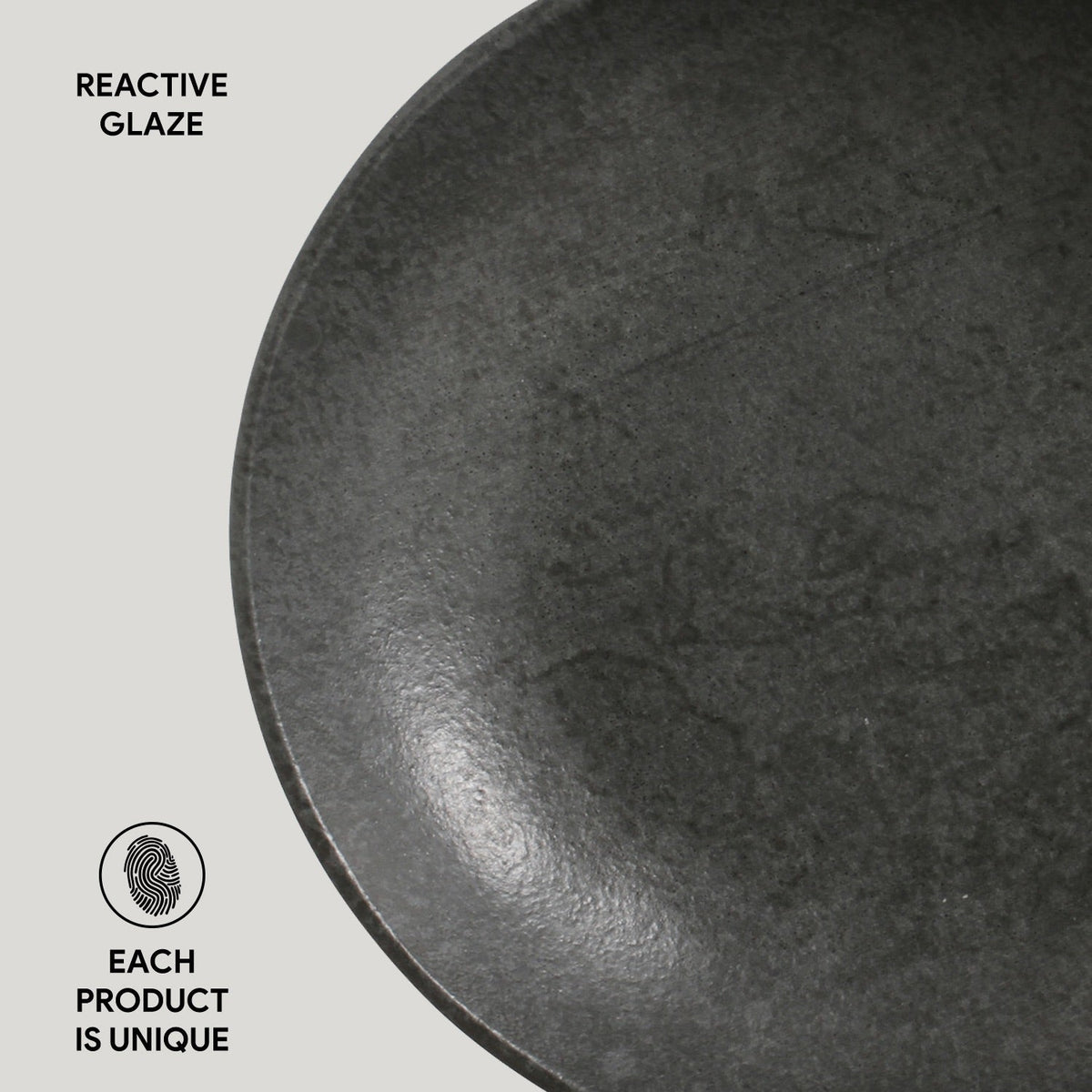 Close-up of a dark gray ceramic plate with 'Reactive Glaze' text and 'Each product is unique' label.