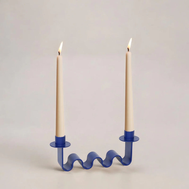 Blue wavy candle holder with two lit candles on a light gray background