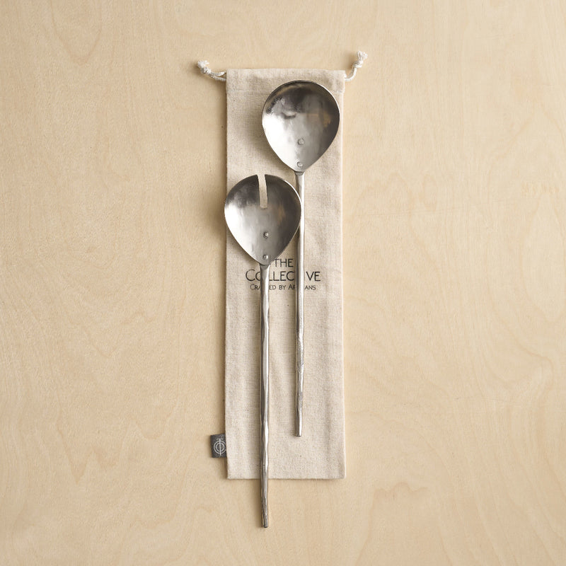 Pewter Serving Spoons with a cloth bag on a wooden surface