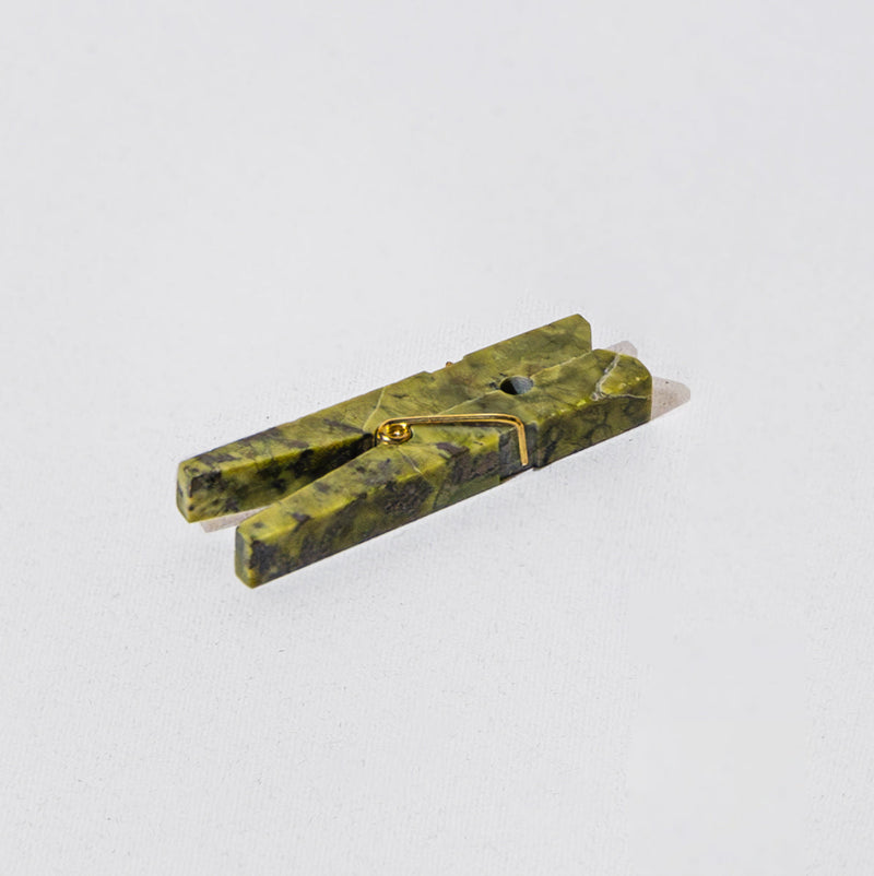 Green Stone clothespin on a light grey background