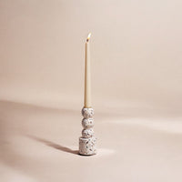 Terrazzo candle holder with a lit candle on a beige background